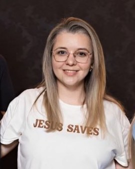 Viviane, proprietária da Infotec, sorrindo, de óculos e camiseta branca.